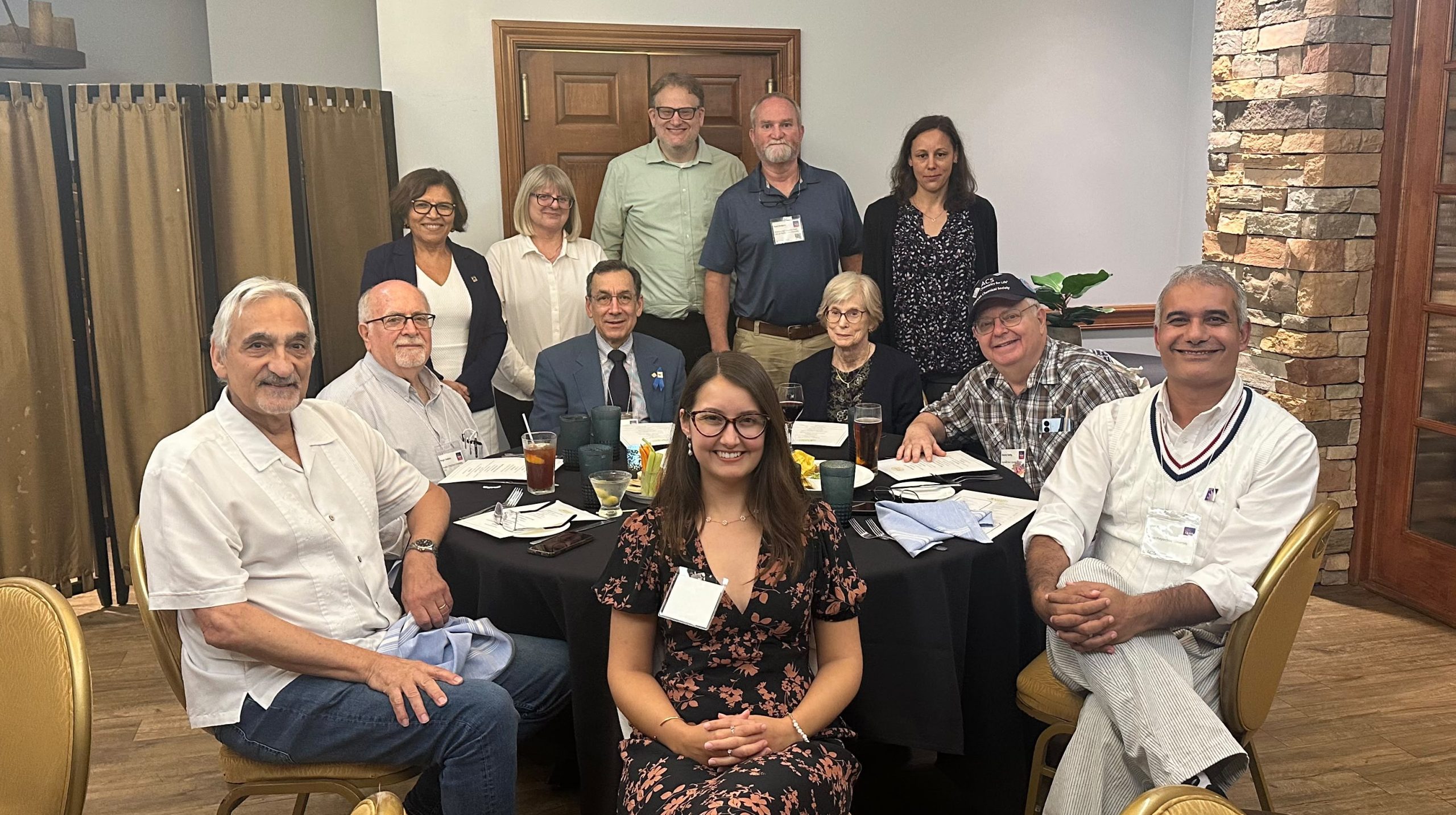 Group photo of FL-ACS members and guests seated and standing around a round table at the 50+ Year Member Recognition Dinner during FAME 2026.